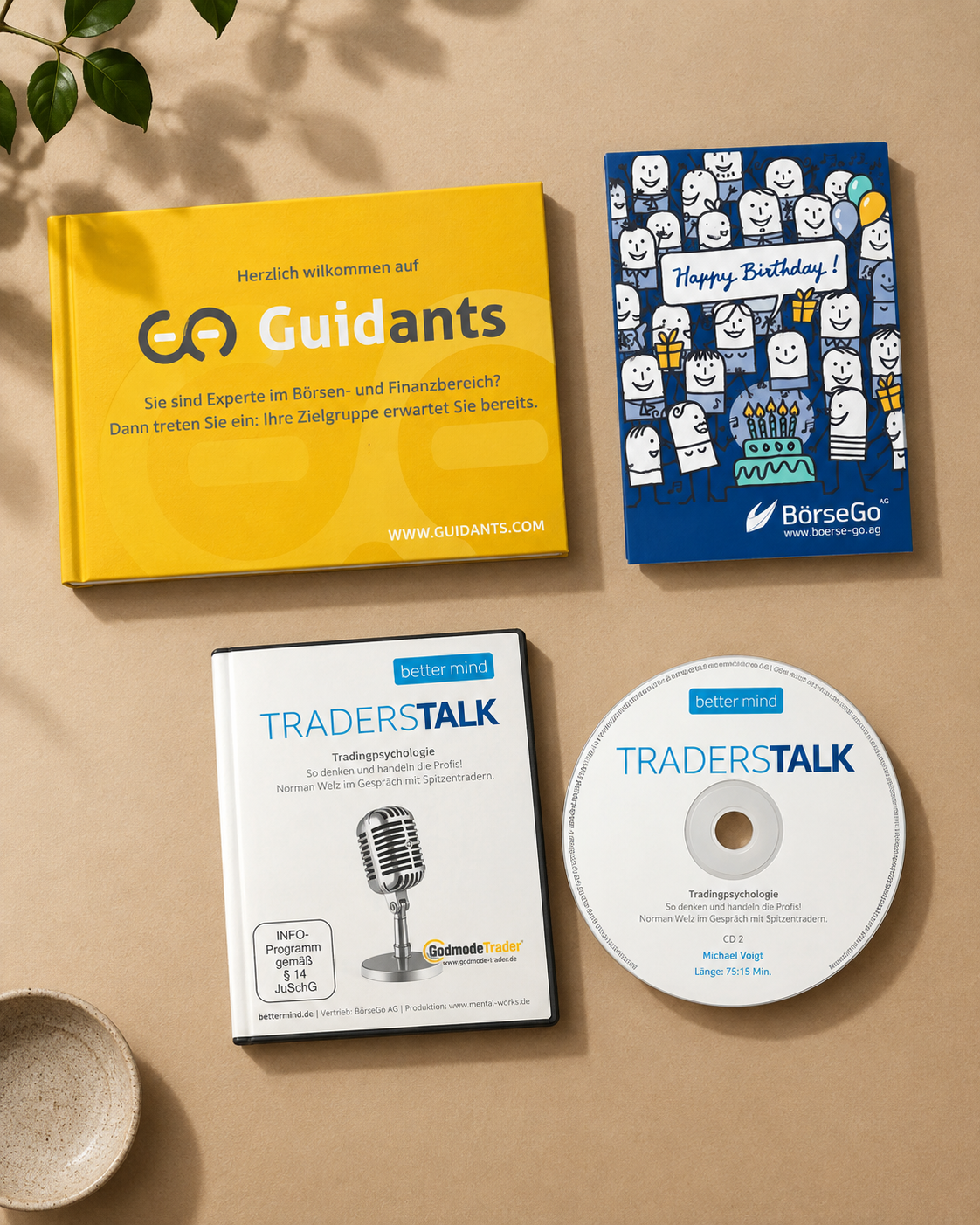 Print-Collage mit Guidants-Buch, Geburtstagskarte und Traderstalk-DVDs auf braunem Papierhintergrund